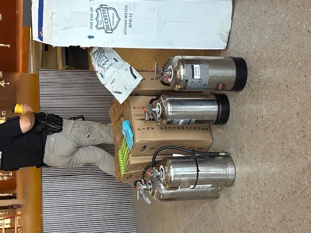 Stainless steel kitchen fire extinguishers lined up for service in a restaurant