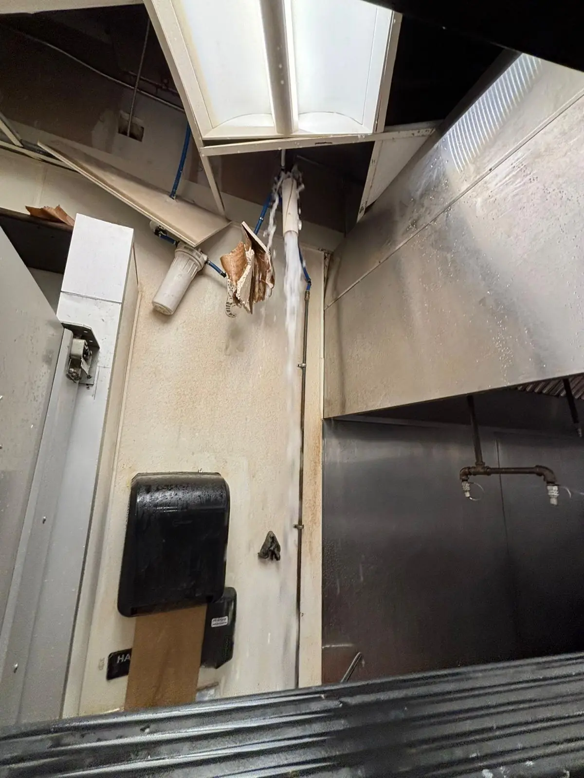 Commercial kitchen ceiling opened beside the hood during fire protection work