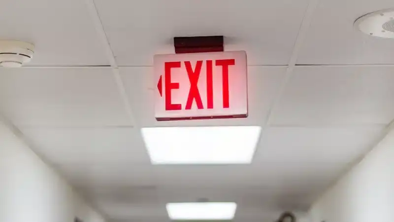 Illuminated exit sign in a commercial hallway, emphasizing workplace safety and fire evacuation routes.