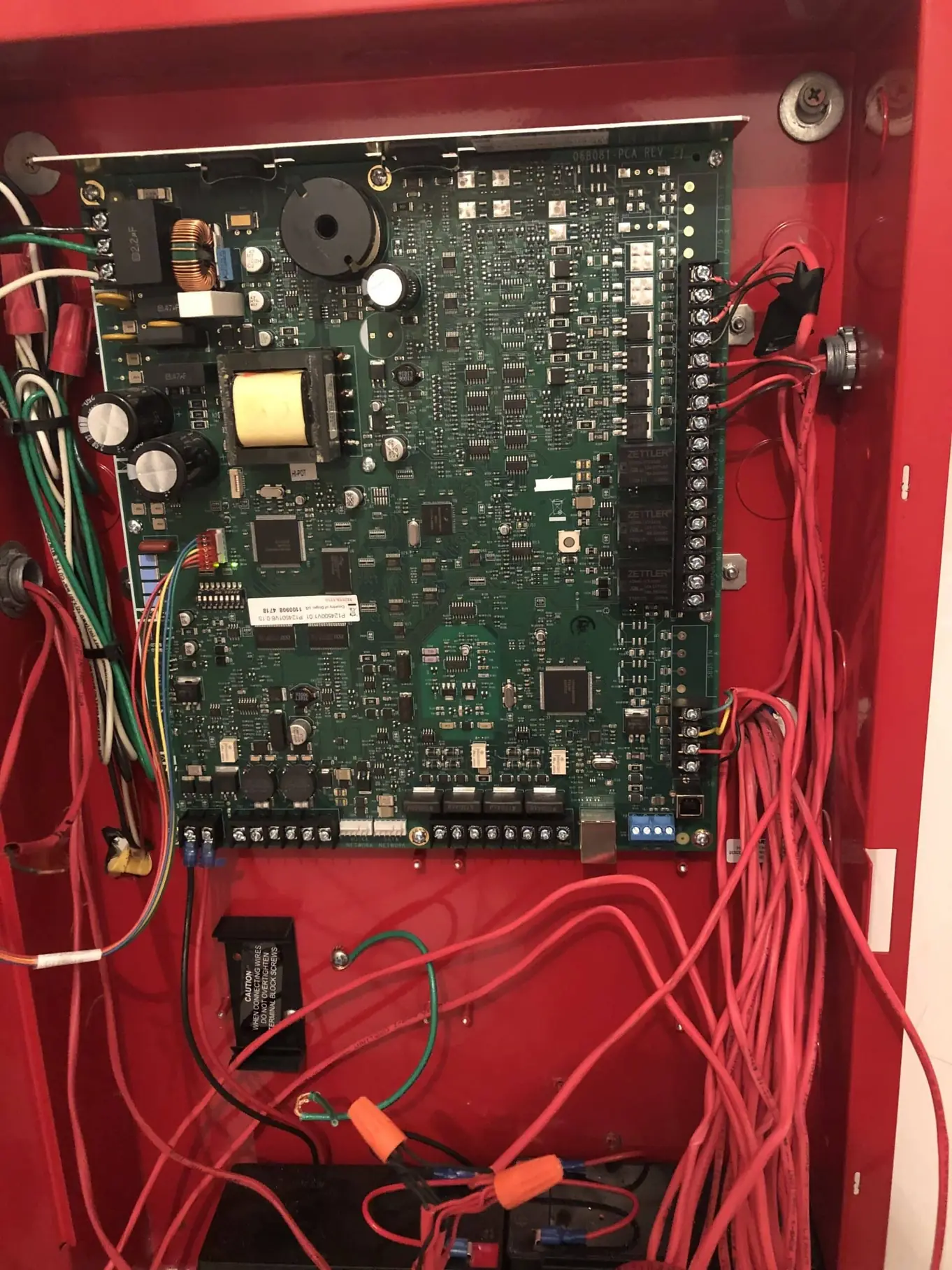 Open fire alarm control panel showing its circuit board and field wiring