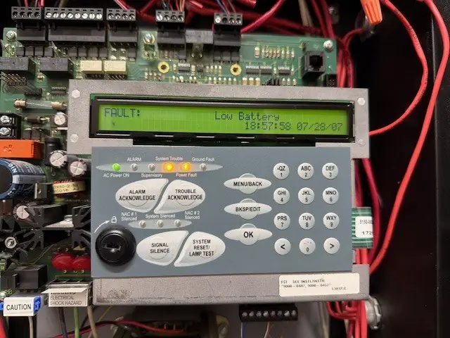 Fire alarm control panel display showing a low battery fault