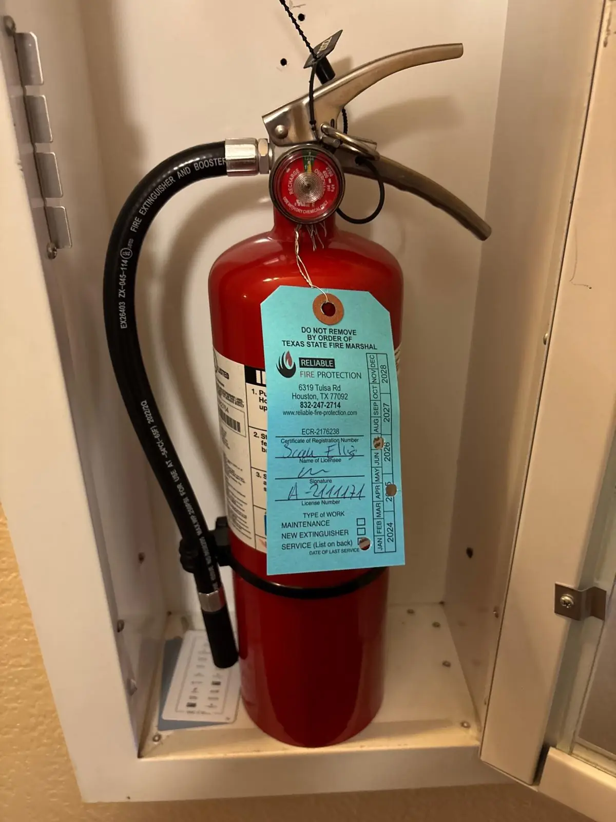Fire extinguisher in a wall cabinet with a current inspection tag
