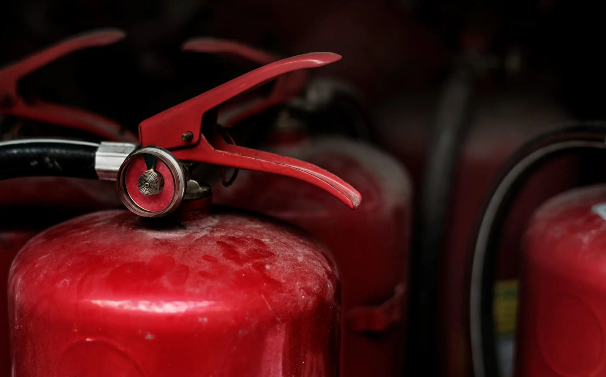 Red fire extinguisher with nozzle and pressure gauge, emphasizing fire safety and maintenance for commercial fire protection services.