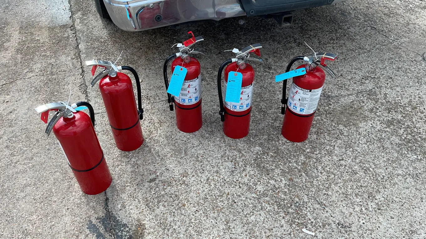Five tagged fire extinguishers lined up for service