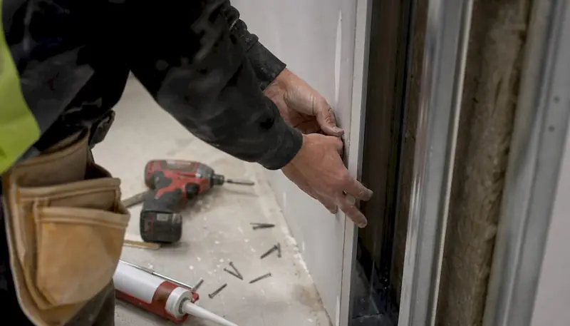 Hands installing fire-rated drywall panel