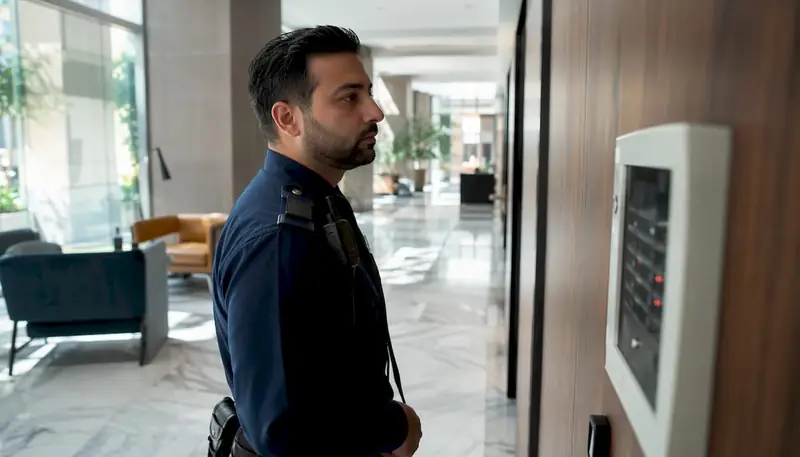 Security guard checking alarm annunciator in lobby