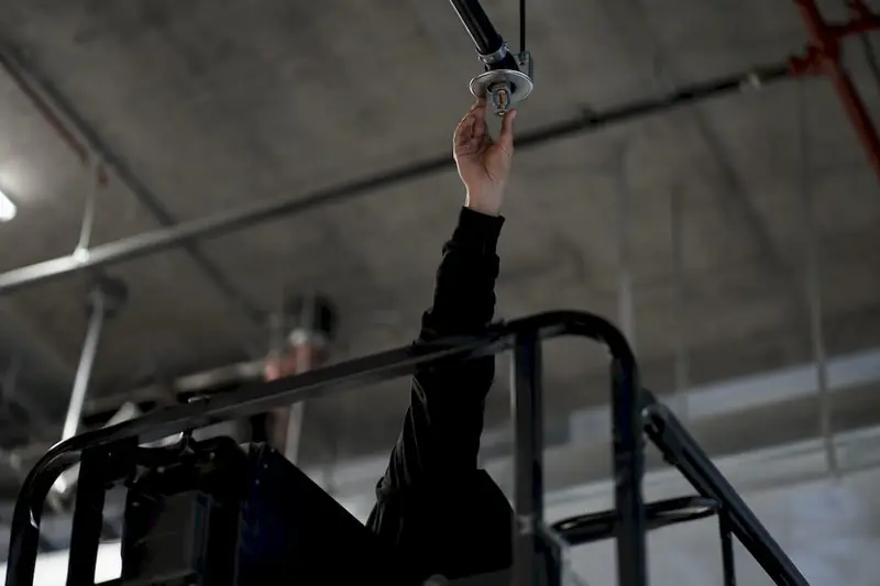 Worker accessing high sprinkler head with lift