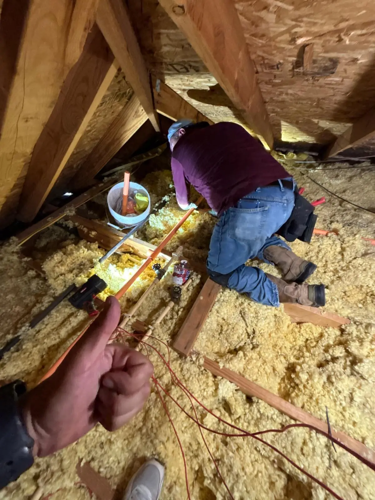Technician installing fire sprinkler piping in an attic