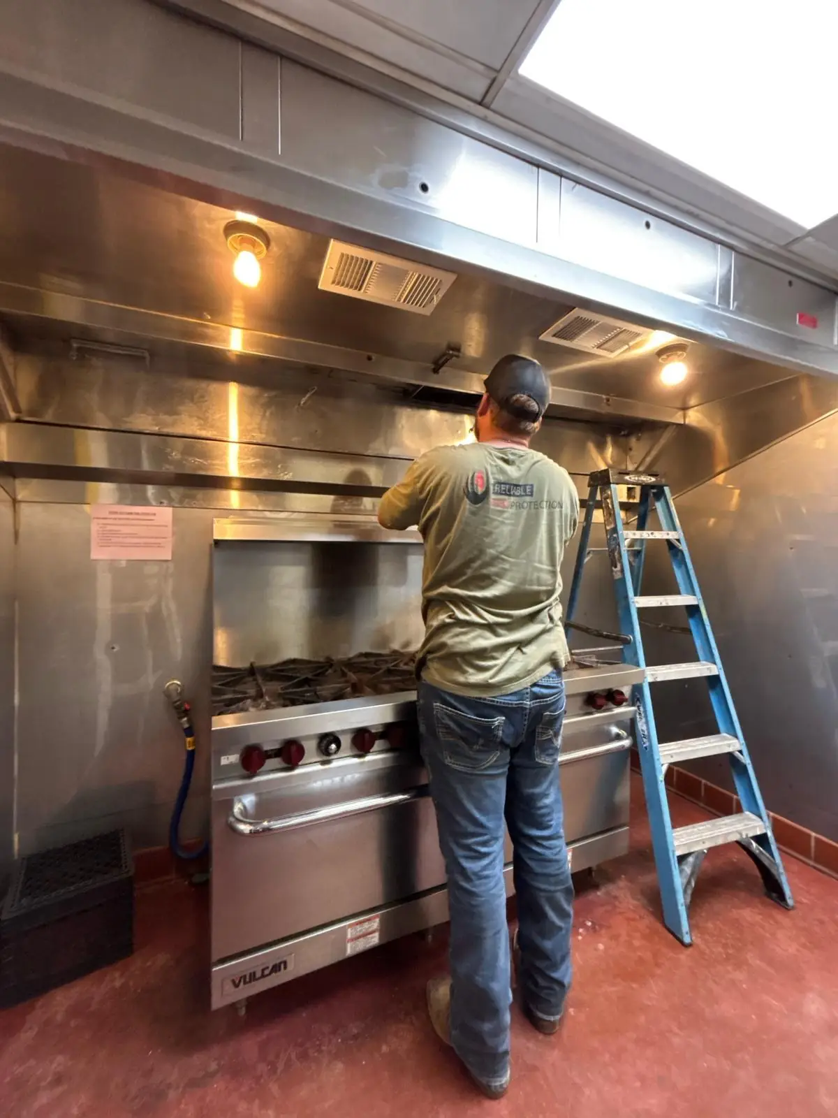 Technician servicing a restaurant kitchen hood suppression system