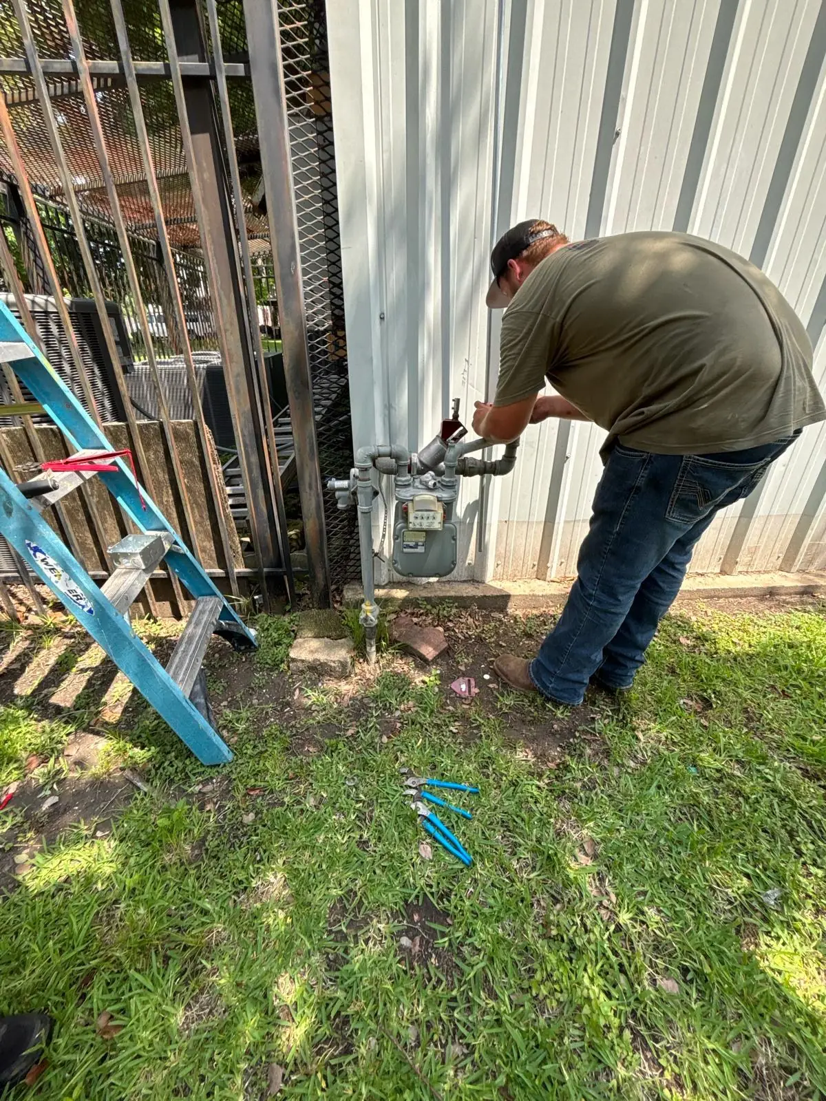 Technician working on outdoor piping beside a commercial building