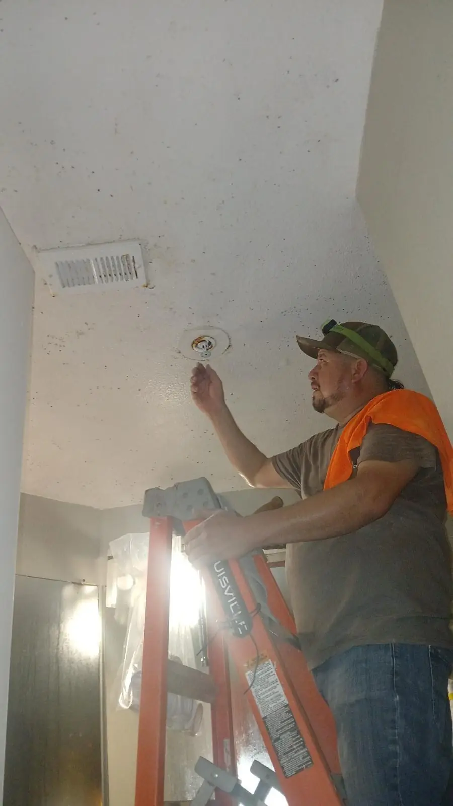 Technician on a ladder replacing a ceiling sprinkler head