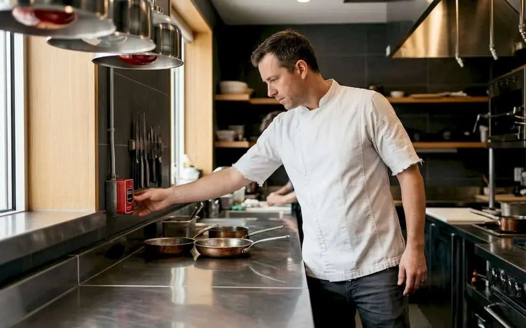 Chef reaching for a kitchen fire suppression pull station