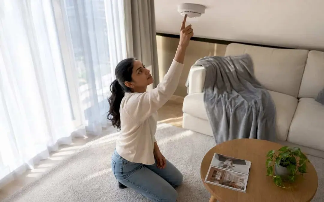 Woman testing a smoke alarm in an apartment living room