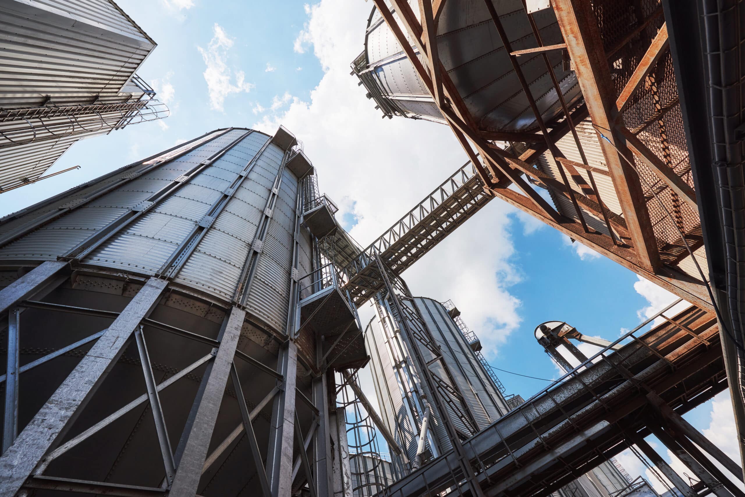 Agricultural Silos. Building Exterior. Storage and drying of grains, wheat, corn, soy, sunflower against the blue sky with white clouds roof replacement by gold shield roofing