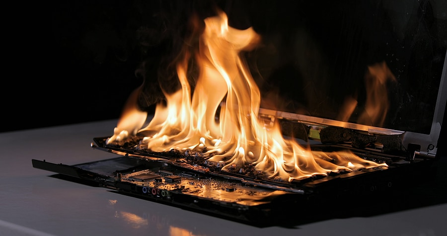 Laptop burning in flames on a desk, fire hazard. losing valuable